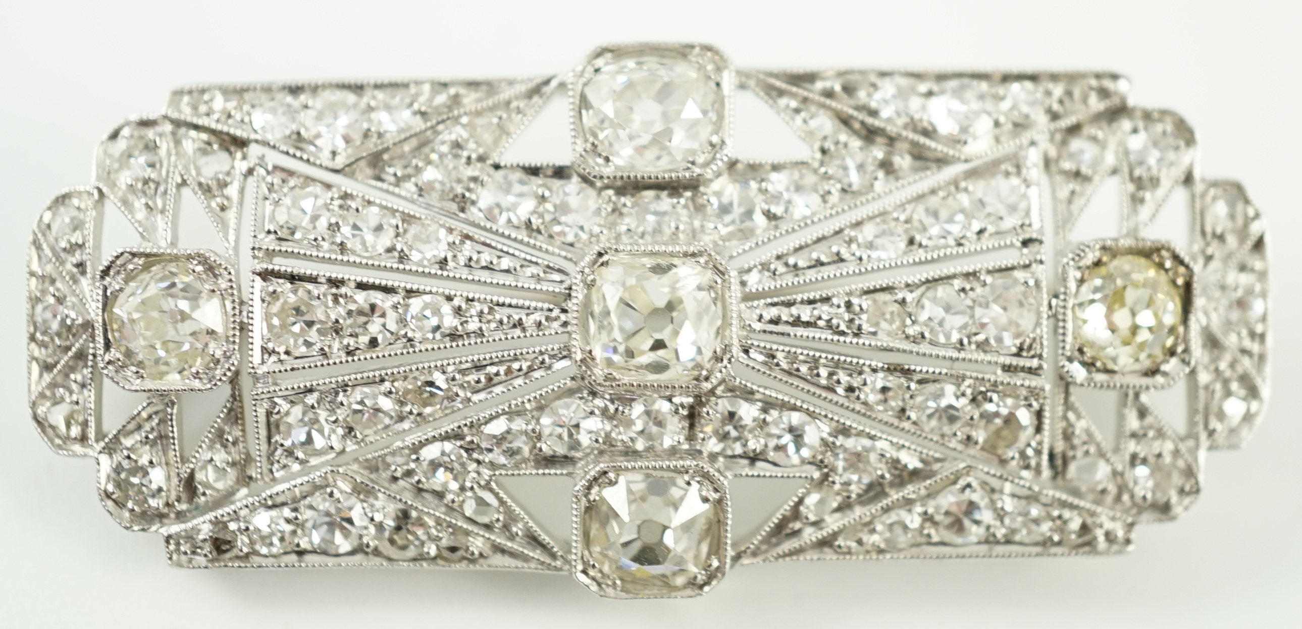 An Art Deco pierced platinum and millegrain set diamond cluster shaped rectangular brooch